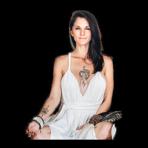 Woman with long dark hair wearing a white wrap dress and decorative accessories, sitting against a black background