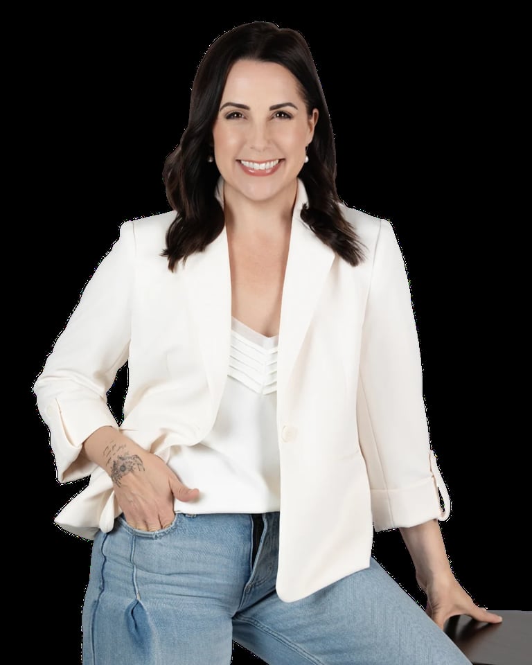 Professional headshot of a smiling woman with dark hair wearing a white blazer and jeans against a black background