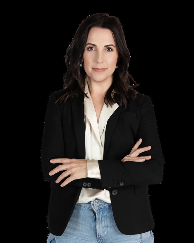 Professional headshot of a woman with dark wavy hair wearing a black blazer and white blouse with arms crossed against a black background